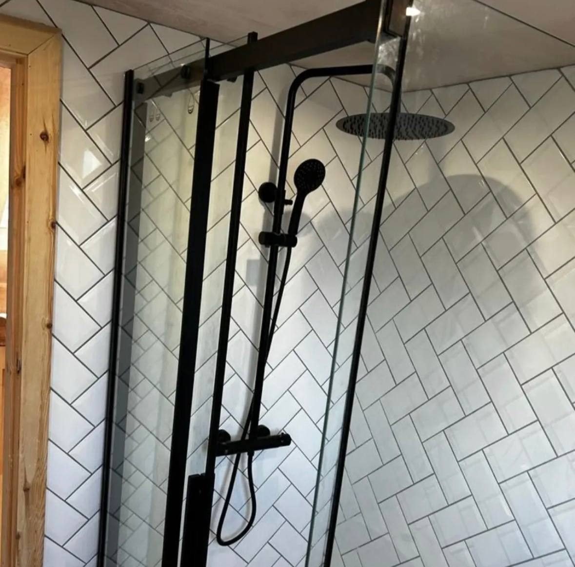 Black rail shower in a herringbone tiled shower enclosure
